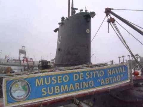 Submarine museum exhibit with banner "Museo de Sitio Naval Submarino Abtao" in a dockyard setting.