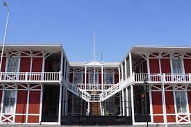 Two-story red building with white accents and central staircase, symmetrical design, clear blue sky