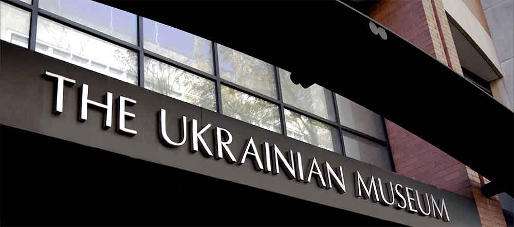 Entrance sign of The Ukrainian Museum with modern typography, large windows, and brickwork background