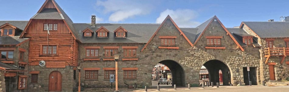A building with wooden and stone elements, peaked roofs, dormer windows, and multiple archways below.