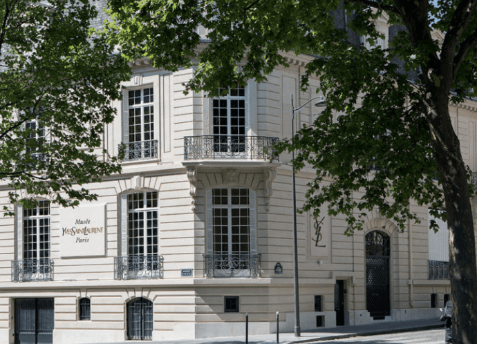 Beige French-style building framed by trees, labeled Yves Saint Laurent Museum, Paris.