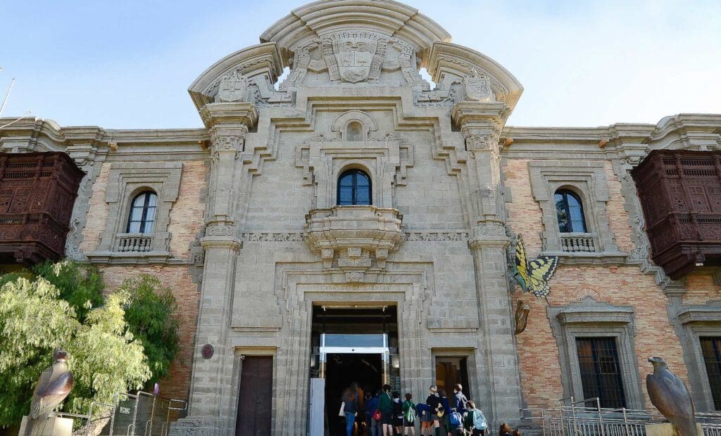 Historical building with arched windows, ornate carvings, butterfly sculpture, and bird statues.