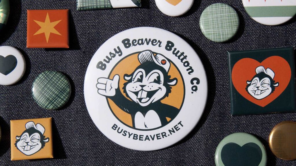 Busy Beaver Button Co. pins and buttons with various designs, cartoon beaver, star, hearts, patterns.