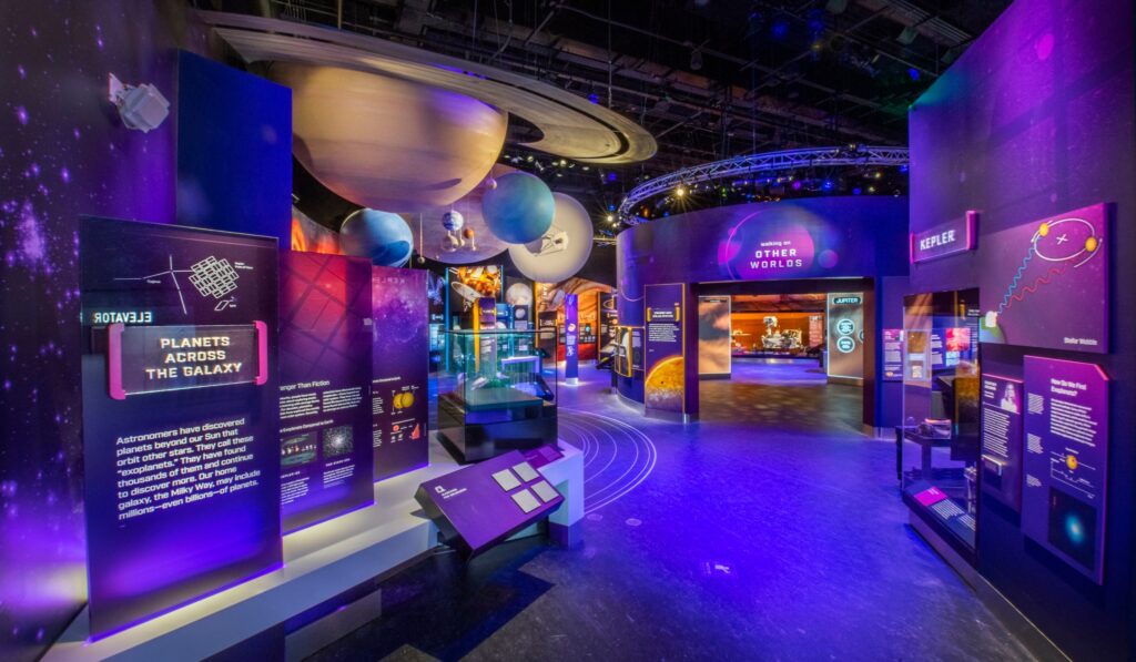 Well-lit exhibit hall on space exploration with models of planets, displays, and interactive elements