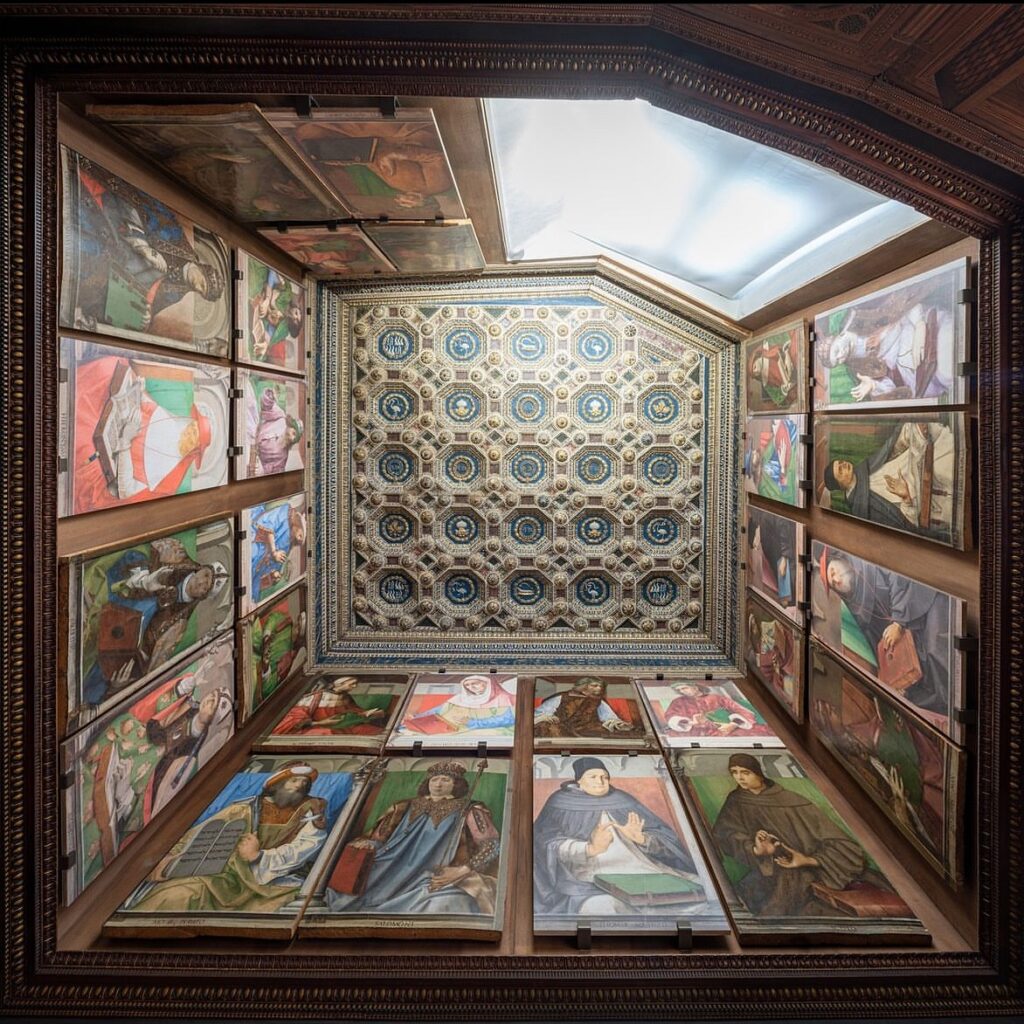 Decorated room with geometric ceiling and framed paintings of figures holding books or scrolls.